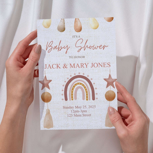 Baby shower invitation held by hands with decorative elements on a plain background