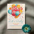 Birthday party invitation with colorful balloons and a flower on a textured surface