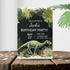 Birthday party invitation with dinosaur and tropical plants on a wooden surface