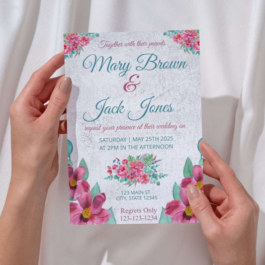 Wedding invitation card with floral design held by hands against a white background