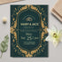 Wedding invitation card with gold decorative elements on a green background, placed on a light surface with flowers and leaves.