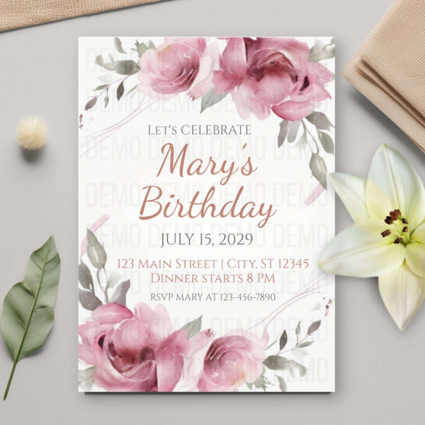 Birthday invitation card with pink flowers on a gray surface