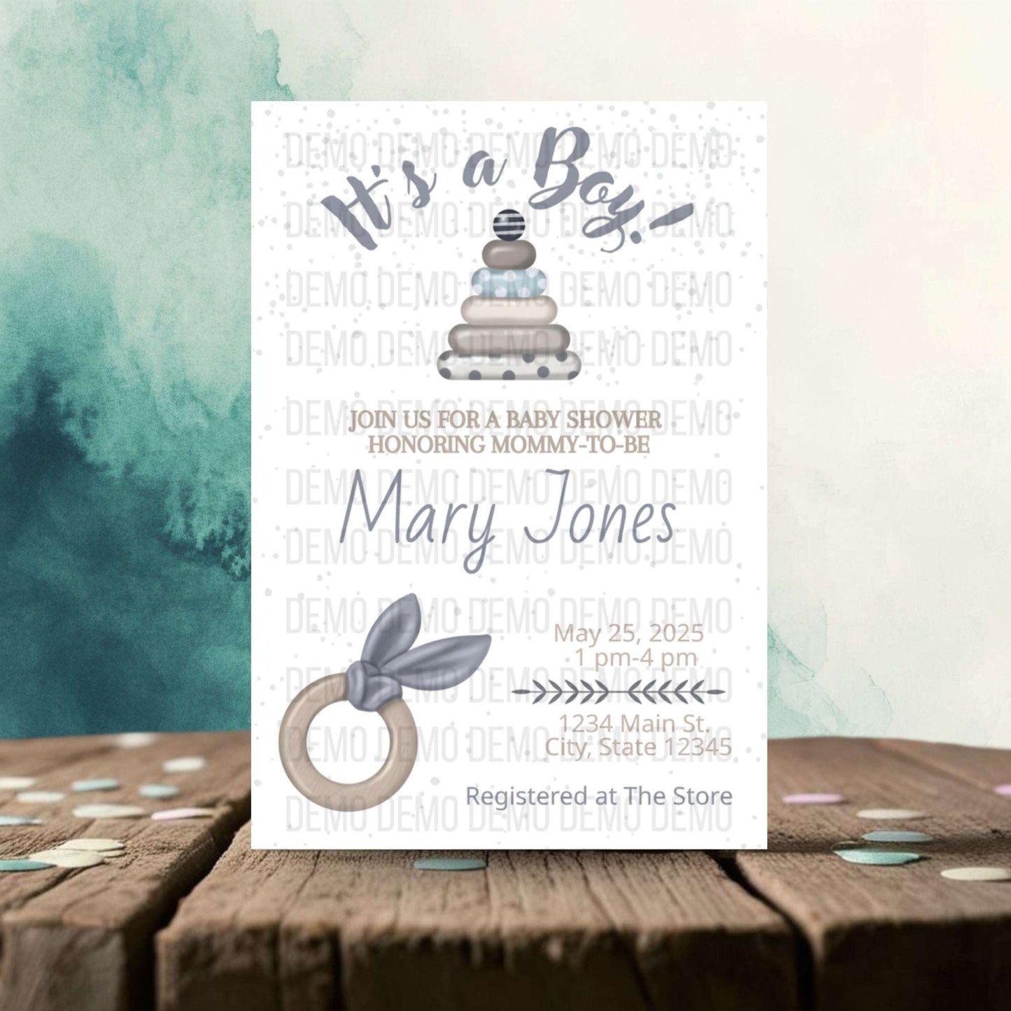 Baby shower invitation for a boy with baby items on a wooden surface