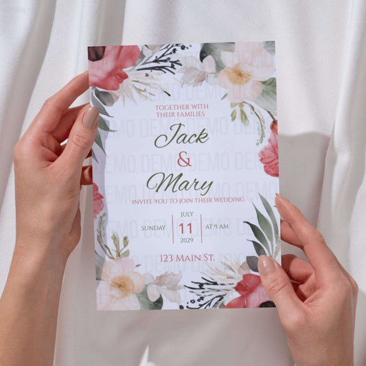 Floral wedding invitation held by hands against a white background