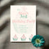 A personalized green-pink cupcake invitation card for a 3rd birthday party laid on a grey surface with a blue flower decoration.