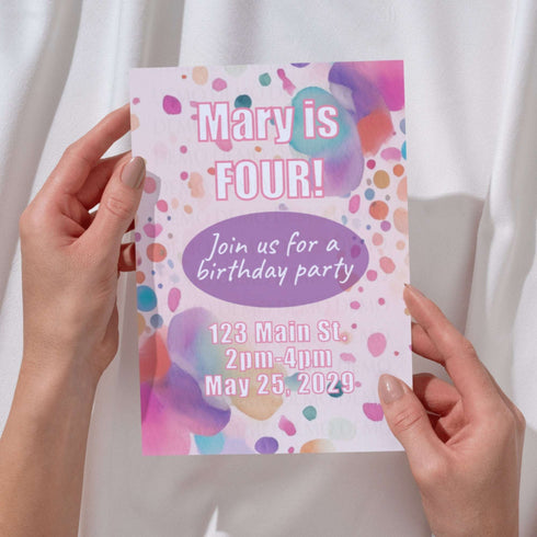 Colorful birthday party invitation held by hands against a white background
