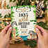 A person holds a safari-themed birthday invitation card featuring illustrations of a lion, zebra, giraffe, and crocodile. The card reads 'Calling All Party Animals! Jack's Wild Birthday Bash' with event details below, set against a blurred background of party decorations.