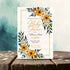 Baby shower invitation with yellow flowers and green leaves on a wooden surface.