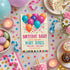 A colorful birthday party invitation card styled in a flat lay with balloons, macarons, cupcakes, candles, confetti, and ribbons on a light gray fabric background.
