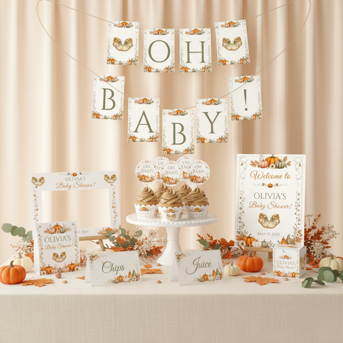 A coordinated autumn baby shower table decoration set with printed signs, cupcake toppers, a photo frame, place cards, and pumpkin accents arranged on a draped beige fabric backdrop.
