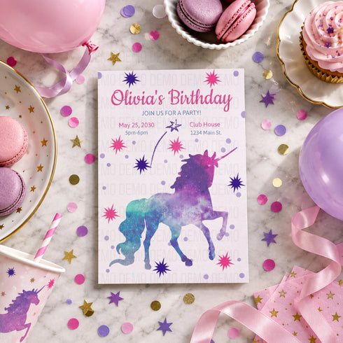 A unicorn-themed birthday invitation card is displayed on a white marble surface surrounded by party decorations, including pink balloons, macarons, cupcakes, confetti, and ribbons. The card features a colorful watercolor-style unicorn illustration and text reading 'Olivia's Birthday'.