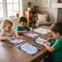 Three children sitting at a table with coloring books and crayons in a home setting.