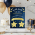 A twin-themed baby shower invitation card styled on a marble surface with balloons, gifts, and confetti. The card has a dark blue starry background with gold text and star graphics.