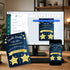 Customizable birthday party invitation templates displayed on a desktop monitor and smartphone screen, with a matching printed card in front on a desk. The design features a navy blue background with yellow stars and banners, and white text, shown in a styled office environment.