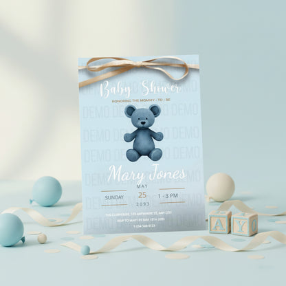 Baby shower invitation with a blue teddy bear on a light blue background, surrounded by decorative ribbons and blocks.