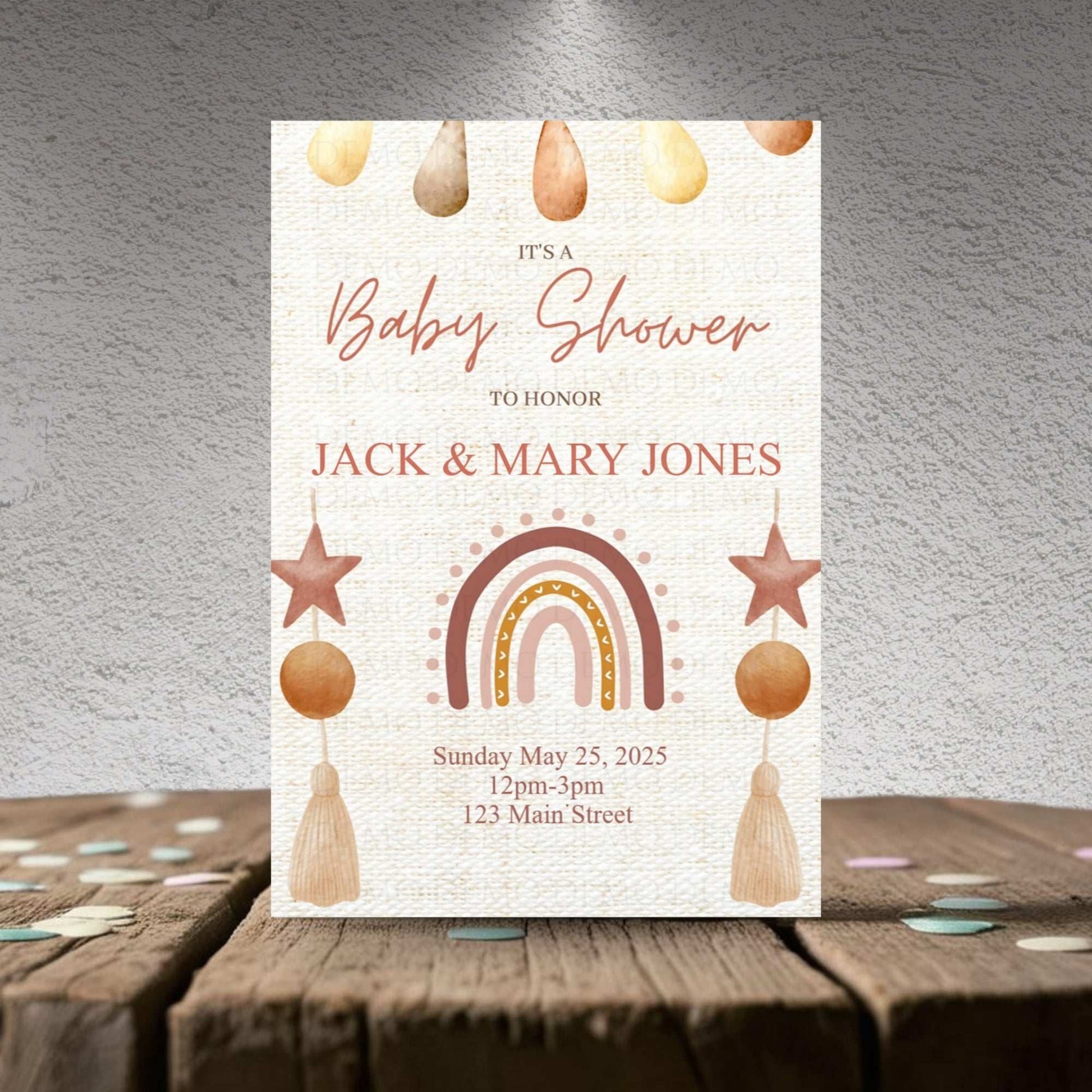 Baby shower invitation with rainbow, stars, and hanging elements on a textured surface.