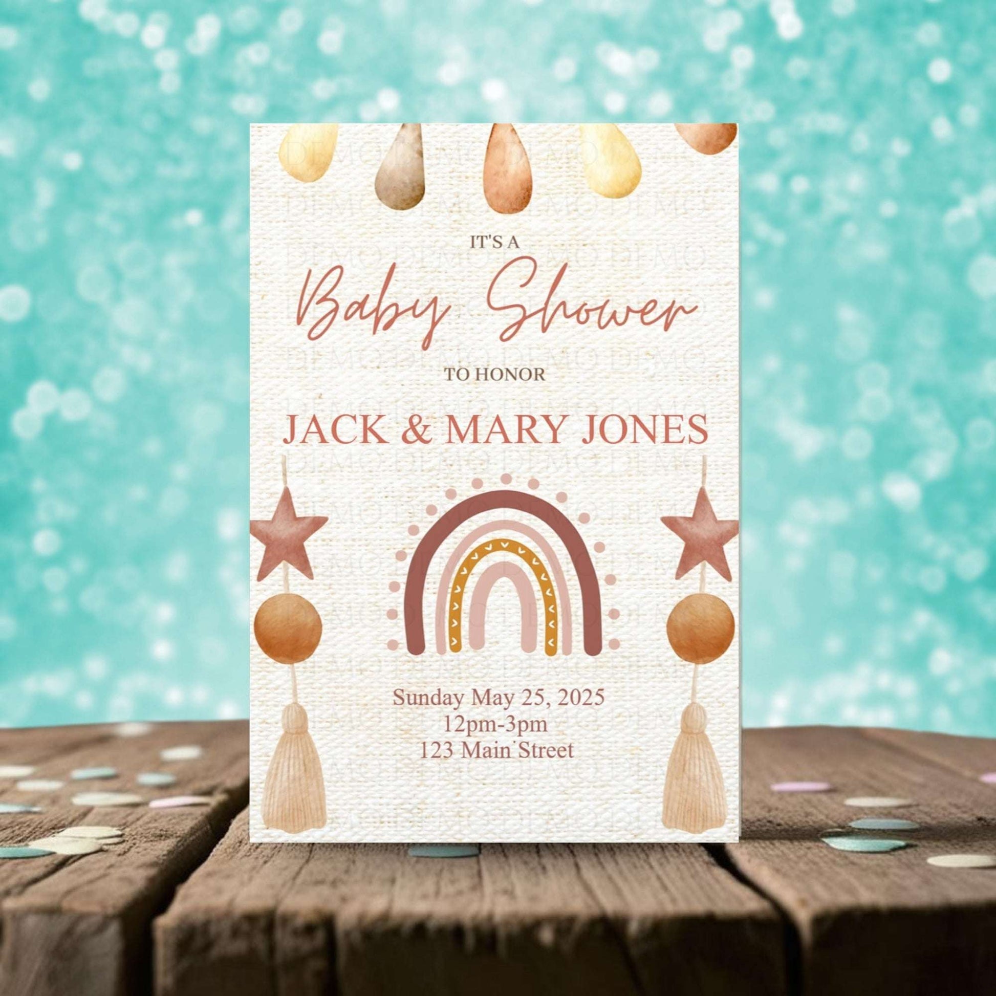 Baby shower invitation with rainbow and star design on a wooden surface with a teal background.