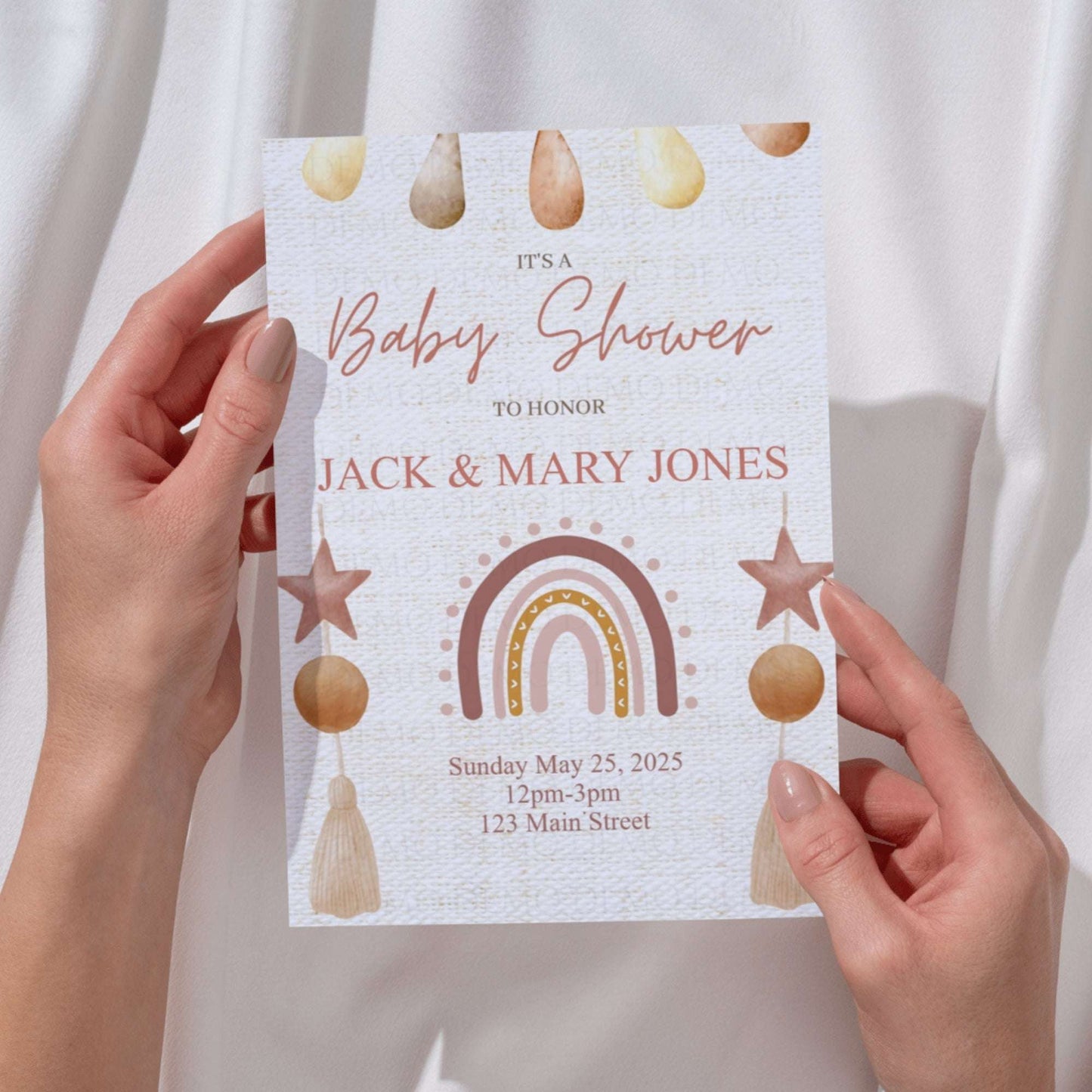 Baby shower invitation held by hands with decorative elements on a plain background