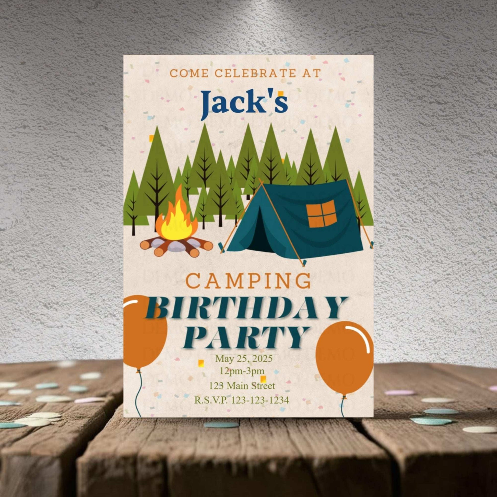 Camping birthday party invitation with trees, tent, and campfire on a wooden surface.