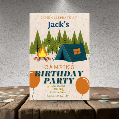 Camping birthday party invitation with trees, tent, and campfire on a wooden surface.
