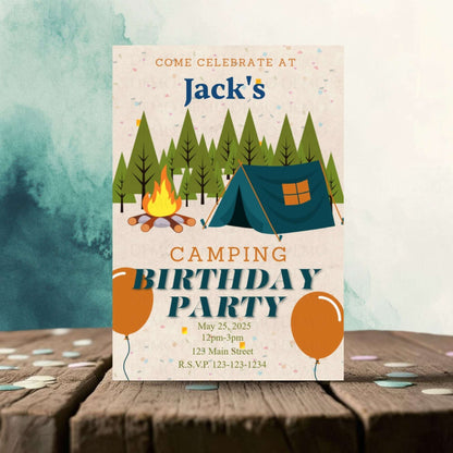 Camping birthday party invitation with tent, campfire, and balloons on a wooden surface.