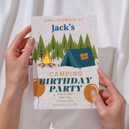 Camping-themed birthday party invitation held by hands against a white background