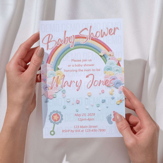 Baby shower invitation with rainbow design held by hands against a white background
