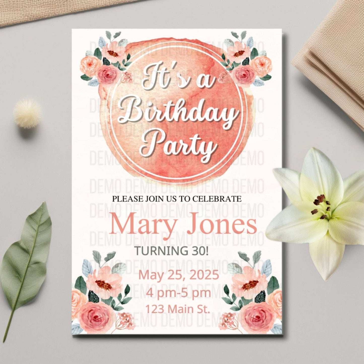Birthday party invitation with floral design on a gray surface with flowers and leaves.