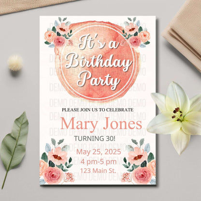 Birthday party invitation with floral design on a gray surface with flowers and leaves.