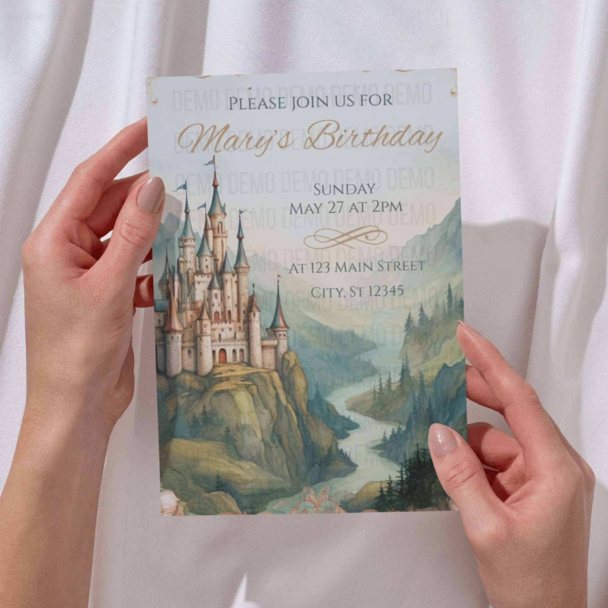 Hand holding a birthday invitation card with a castle design on a white background