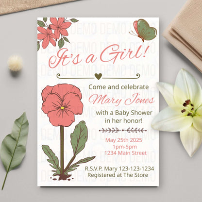 Baby shower invitation with floral design on a light gray surface with flowers and leaves.