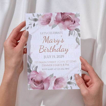 Hand holding a birthday invitation card with floral design
