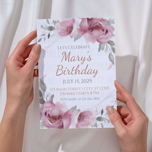 Hand holding a birthday invitation card with floral design