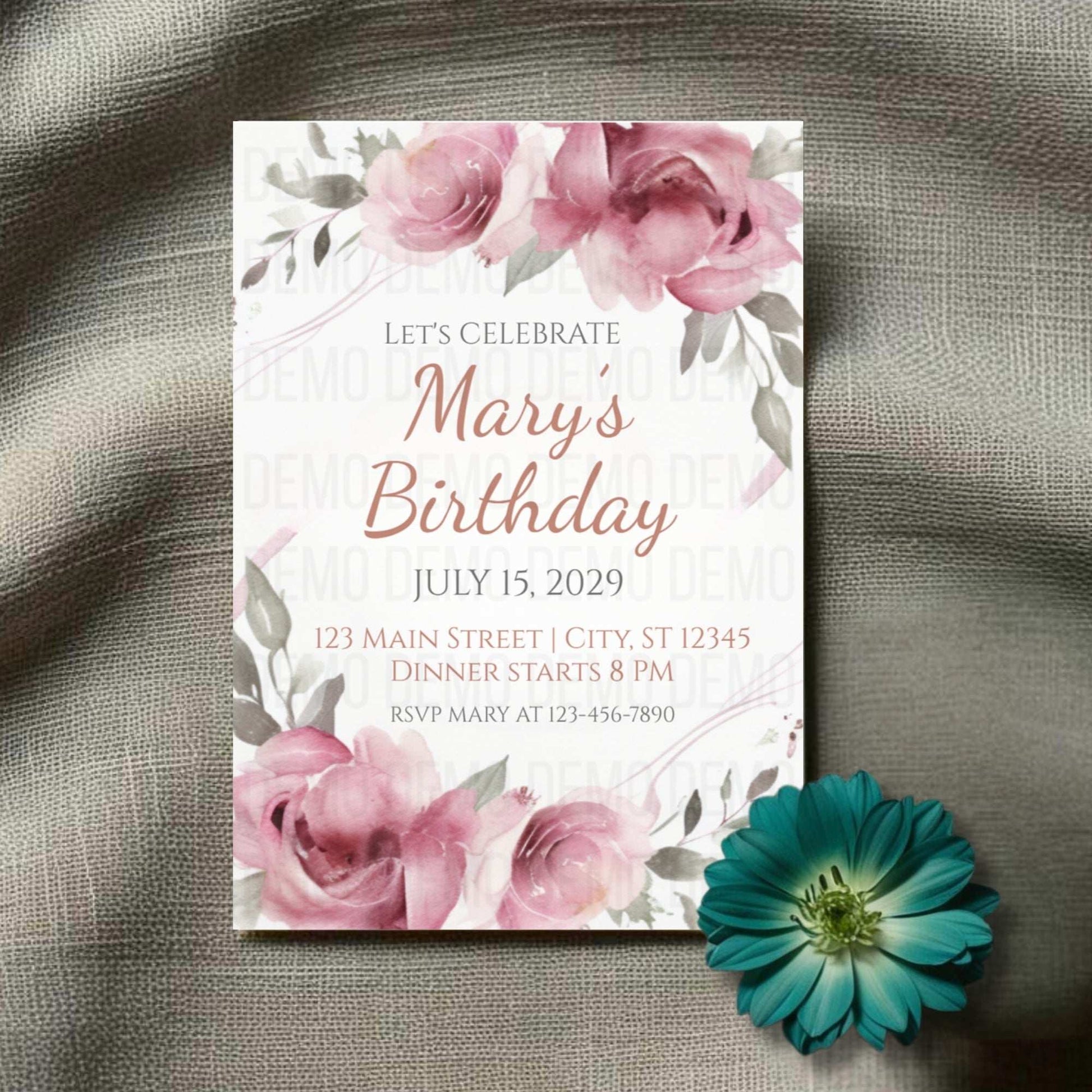 Birthday invitation card with pink flowers on a textured surface with a teal flower.