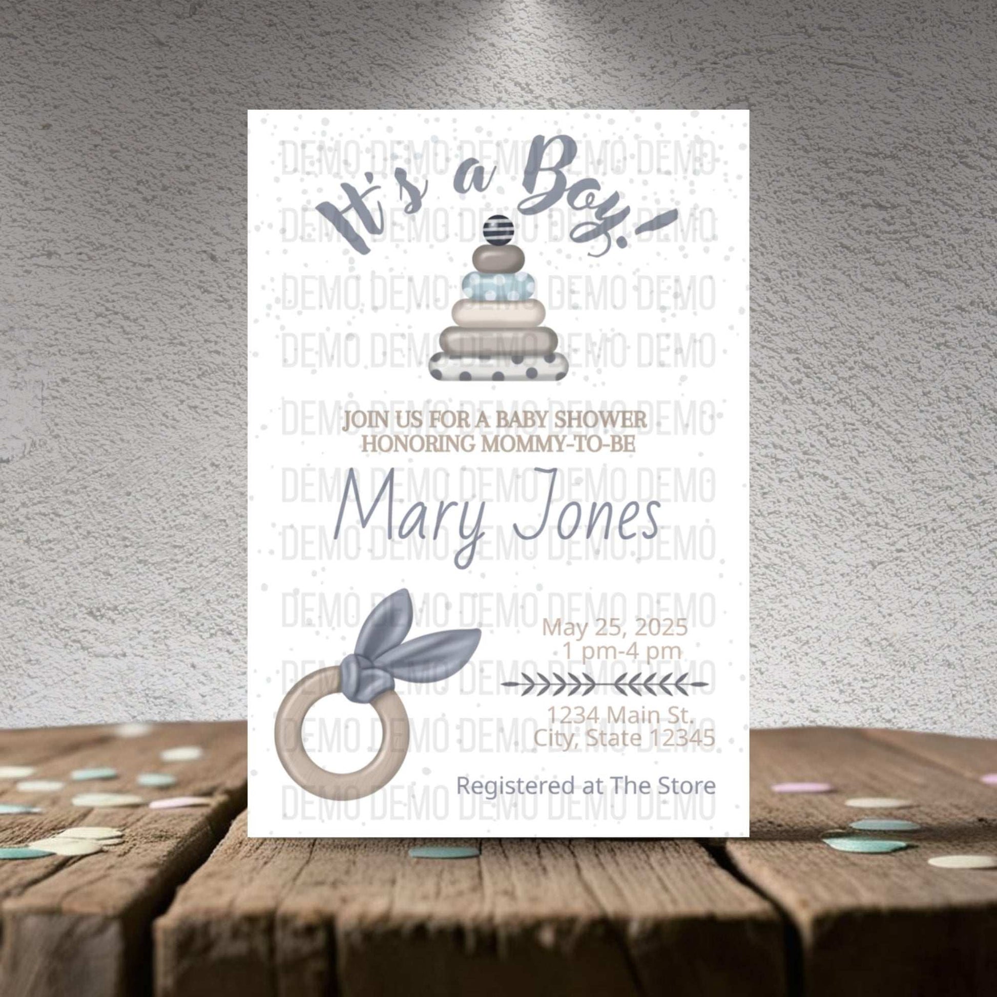 Baby shower invitation for a boy with cake and baby bootie design on a textured surface.