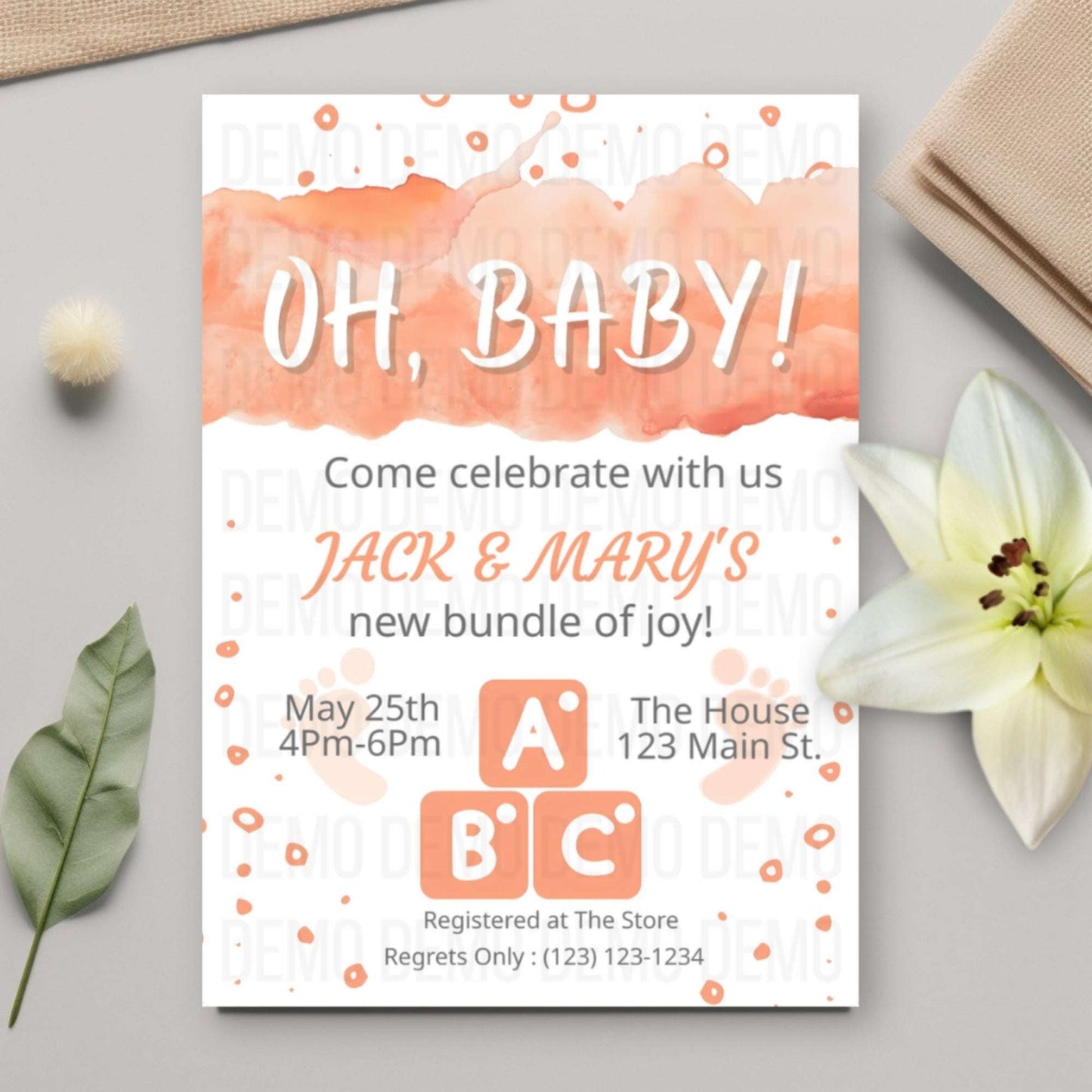 Baby shower invitation with watercolor design on a light gray surface with decorative elements.