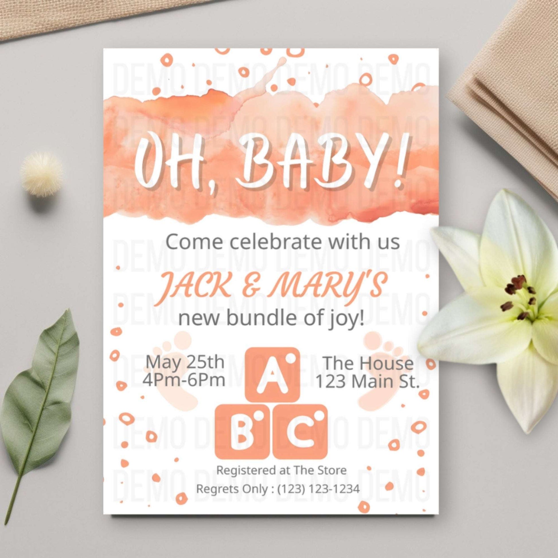 Baby shower invitation with watercolor design on a light gray surface with decorative elements.