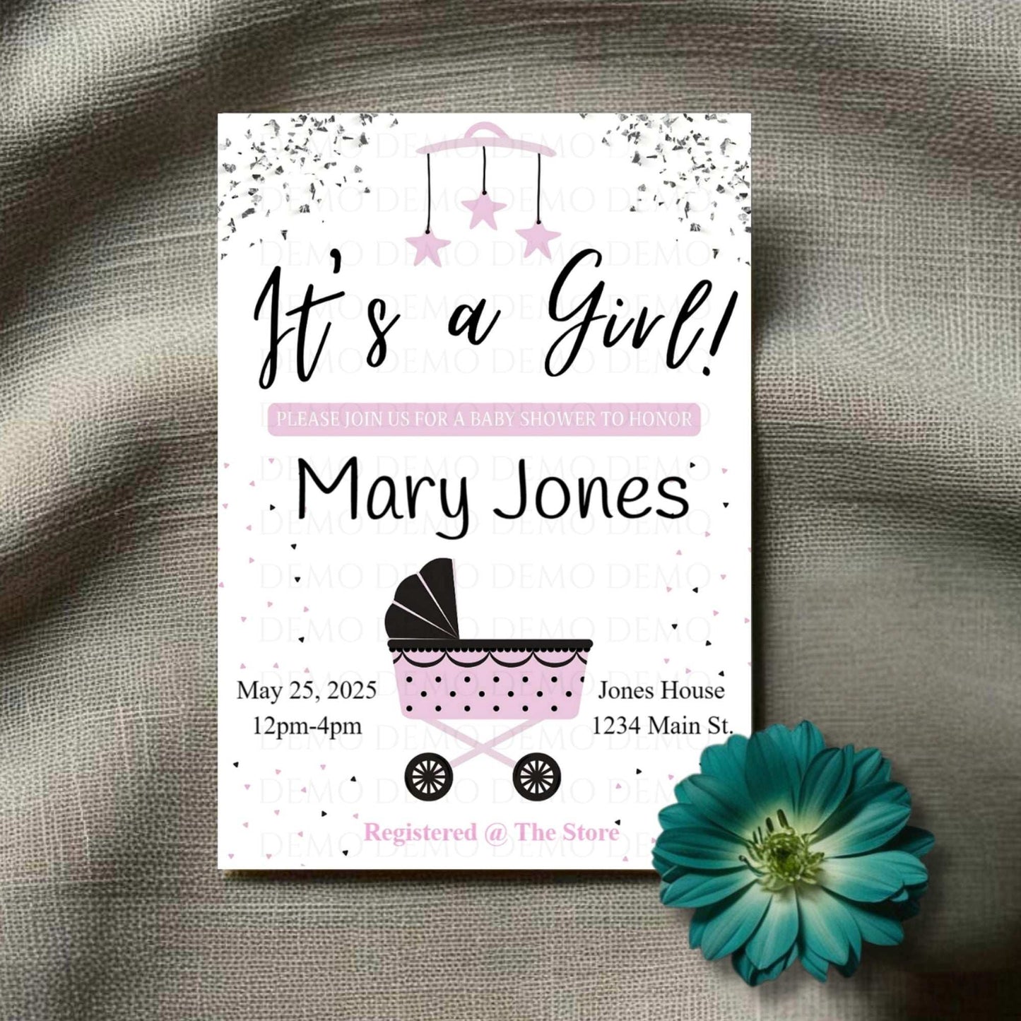 A personalized baby shower invite with the text 'It's a Girl! Mary Jones' along with event details. The invite features a baby buggy design and is placed next to a blue flower.