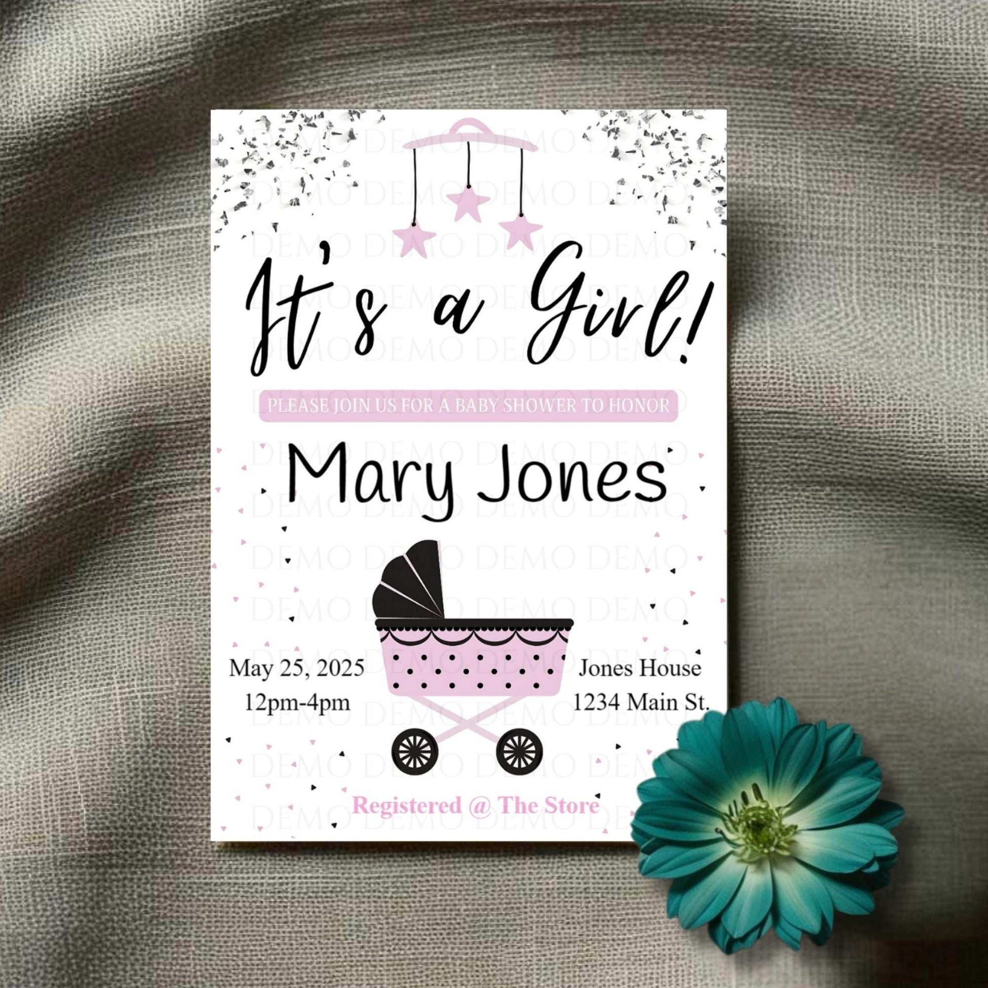 A personalized baby shower invite with the text 'It's a Girl! Mary Jones' along with event details. The invite features a baby buggy design and is placed next to a blue flower.