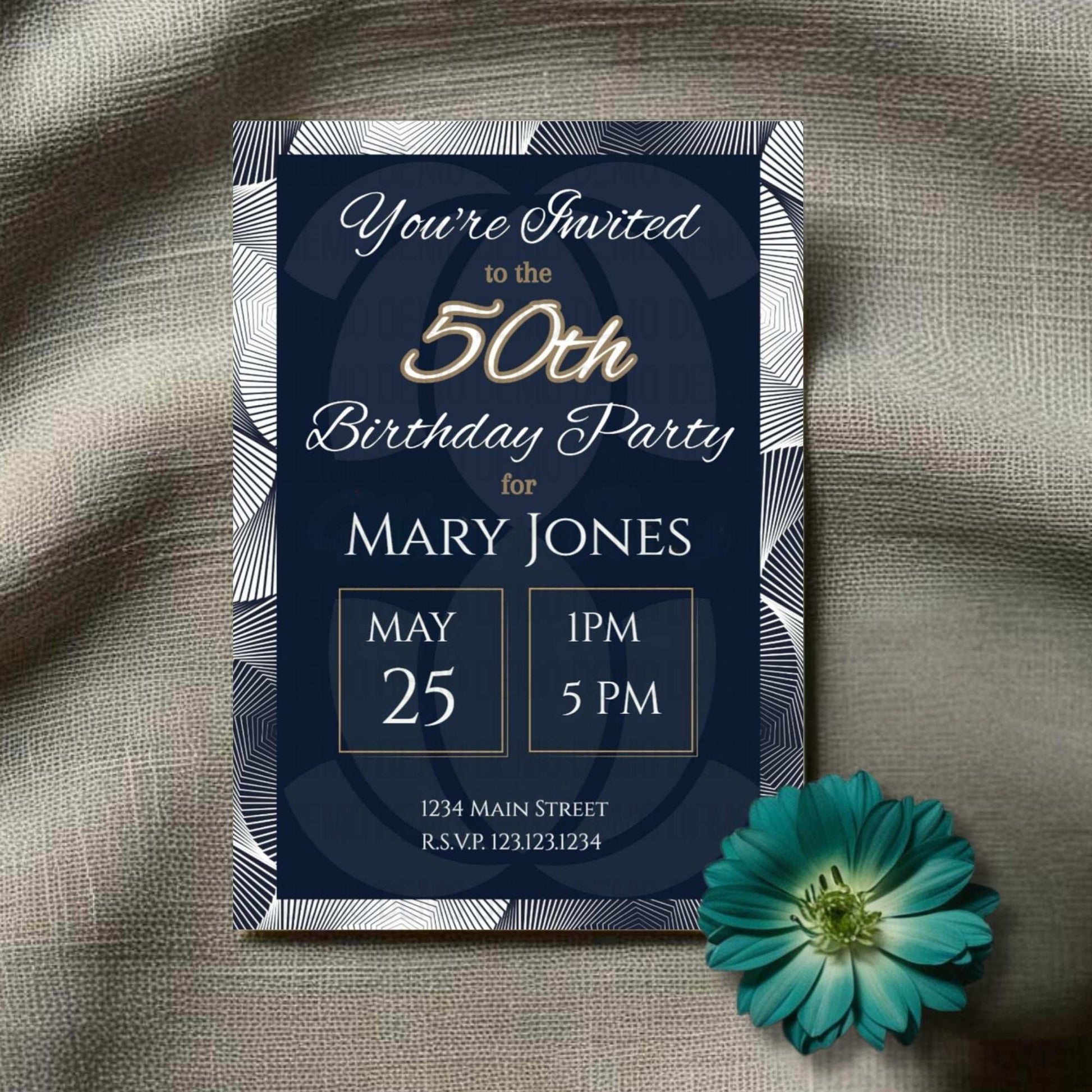 50th birthday party invitation with gold text on a dark blue background, placed on a textured surface with a teal flower.