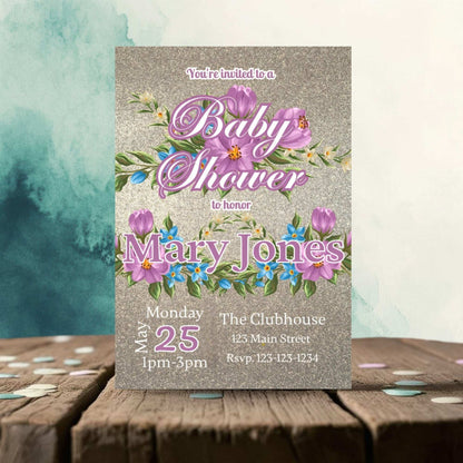 Baby shower invitation with floral design on a wooden surface