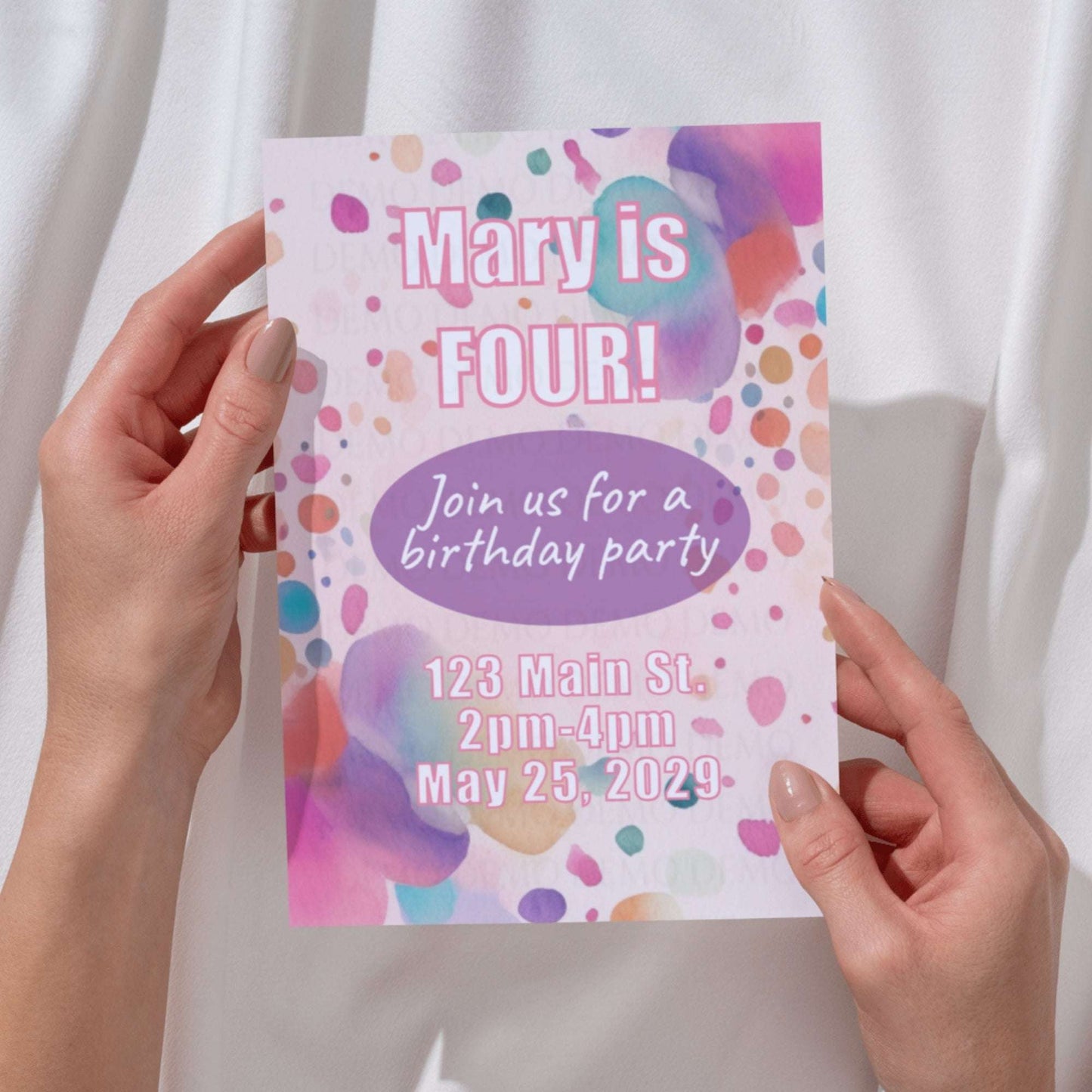 Colorful birthday party invitation held by hands against a white background