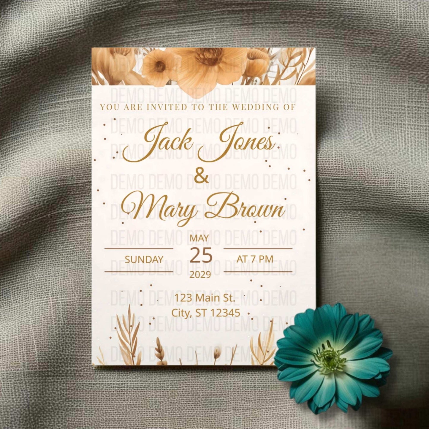 Wedding invitation card with floral design on a textured surface with a blue flower.