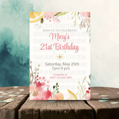 Invitation card for Mary's 21st birthday with floral designs on a wooden surface.