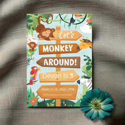Invitation card with monkey theme on a textured surface with a flower.