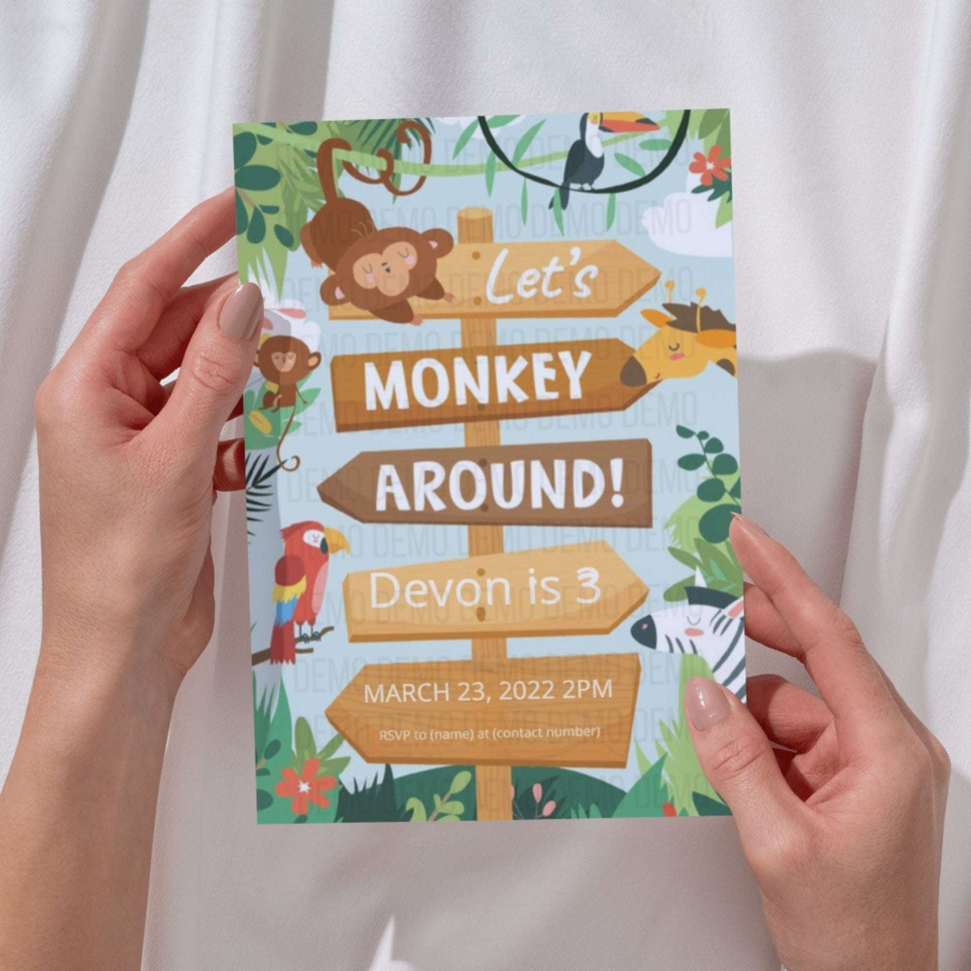 Hand holding a colorful birthday invitation with monkey theme