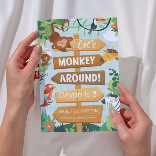 Hand holding a colorful birthday invitation with monkey theme