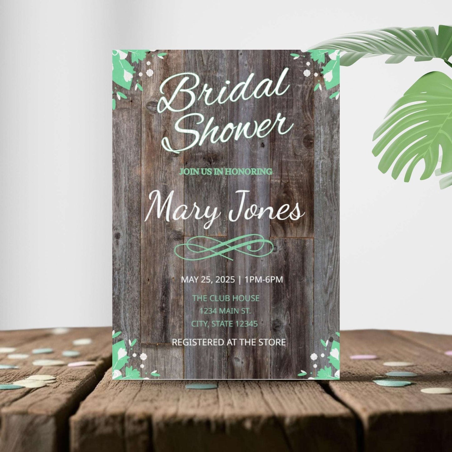 Bridal shower invitation with wooden design and tropical leaves on a wooden surface.